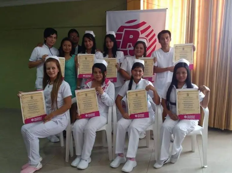 Graduadas de uniforme blanco con sus diplomas