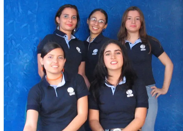 Estudiantes con uniforme institucional posando frente a una pared azul