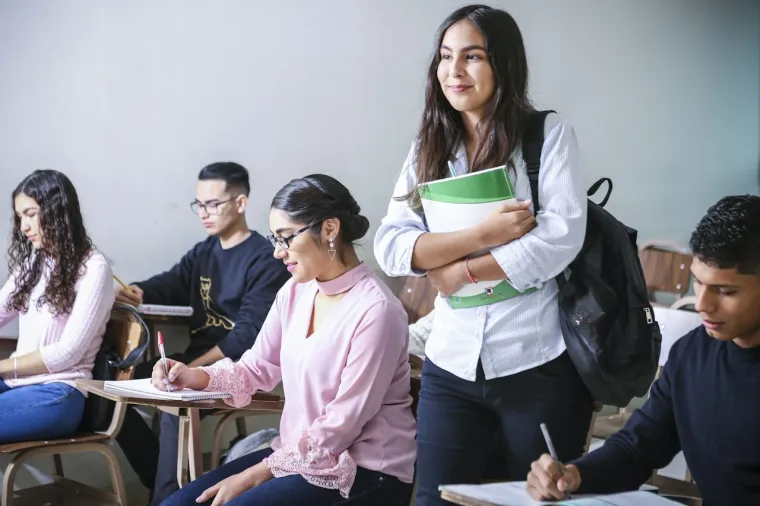 Estudiante concentrada tomando notas frente a su laptop en casa