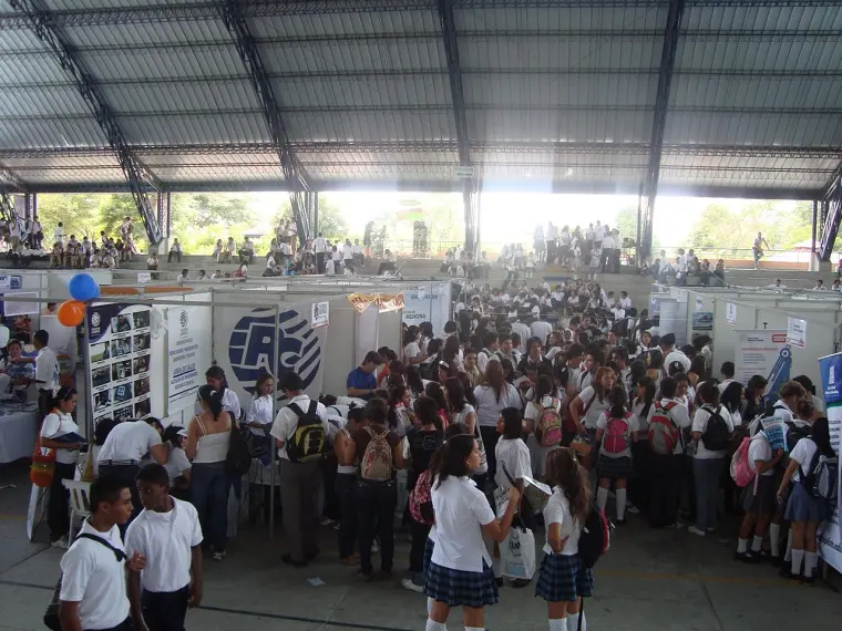 Coliseo lleno de estudiantes visitando los stands de una feria educativa
