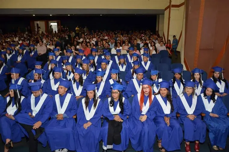 Auditorio lleno durante una ceremonia de grado con graduados de toga azul