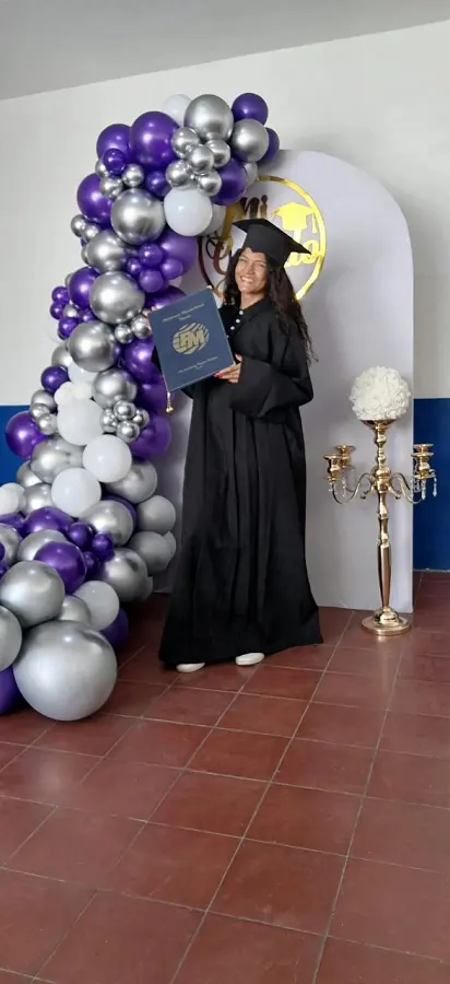 Graduada con toga posando junto a un arco de globos