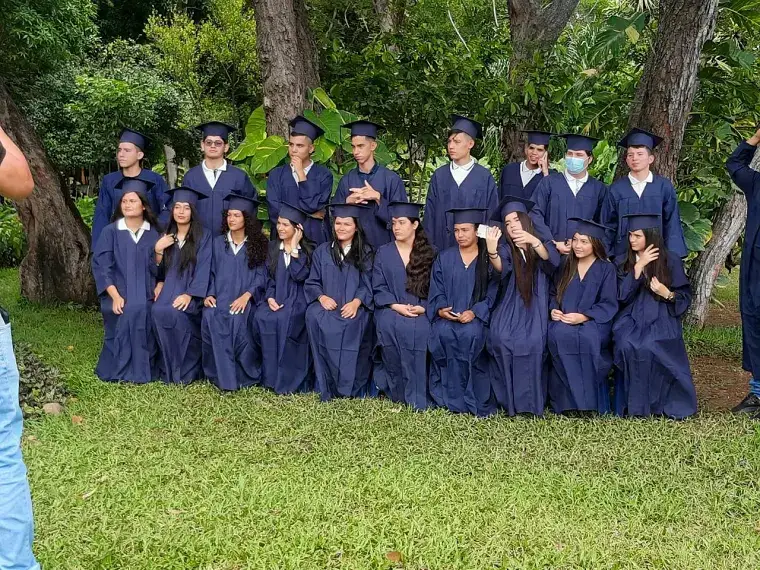 Grupo de graduados con toga azul en un jardín