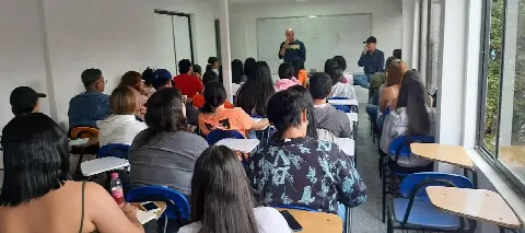 Estudiantes adultos atentos a su docente en un salón de clase