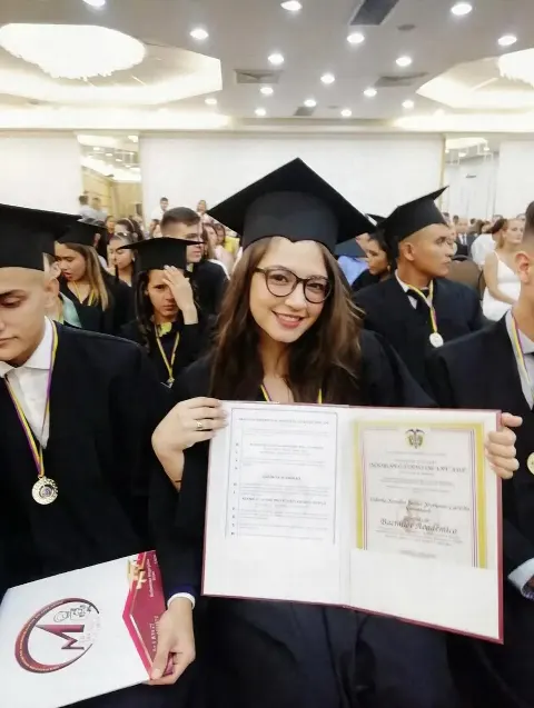 Egresada sonriente con toga y birrete mostrando su diploma