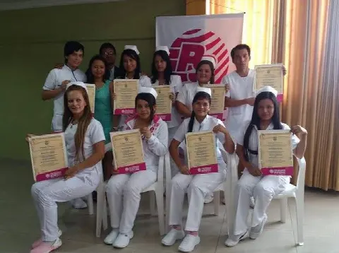 Graduadas de uniforme blanco con sus diplomas