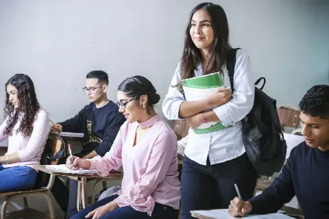 Estudiante concentrada tomando notas frente a su laptop en casa