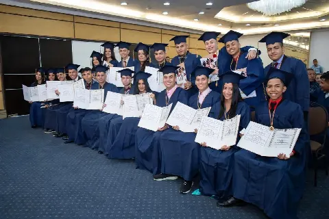 Graduados sentados en un salón mostrando sus diplomas